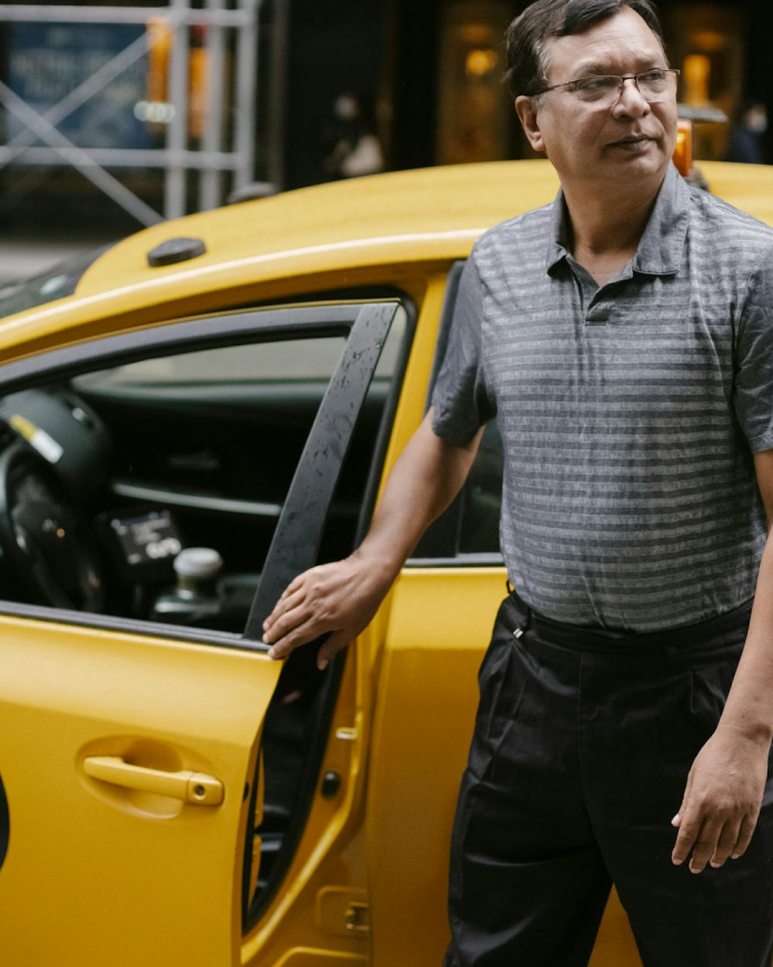 A taxi driver opening the door to welcome a passenger
