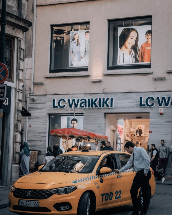 A passenger about to board a taxi on a busy commercial street